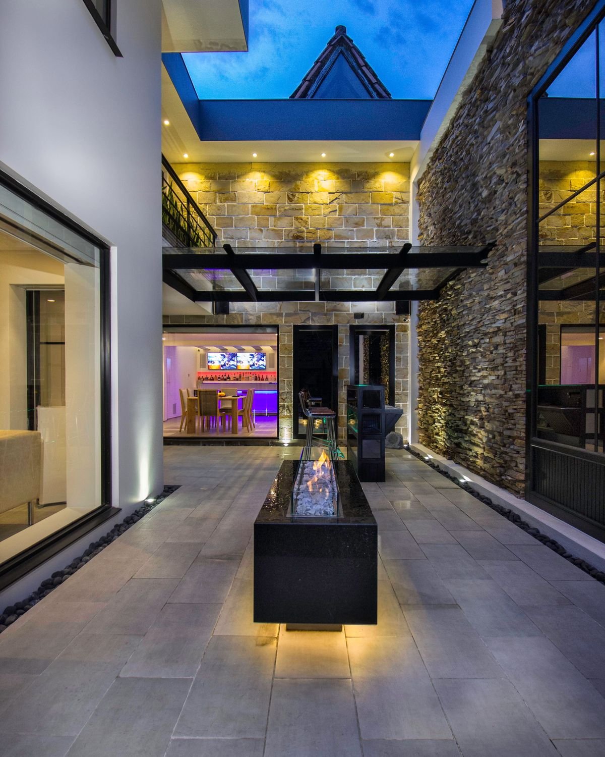 Courtyard with stone walls and a fire feature at dusk